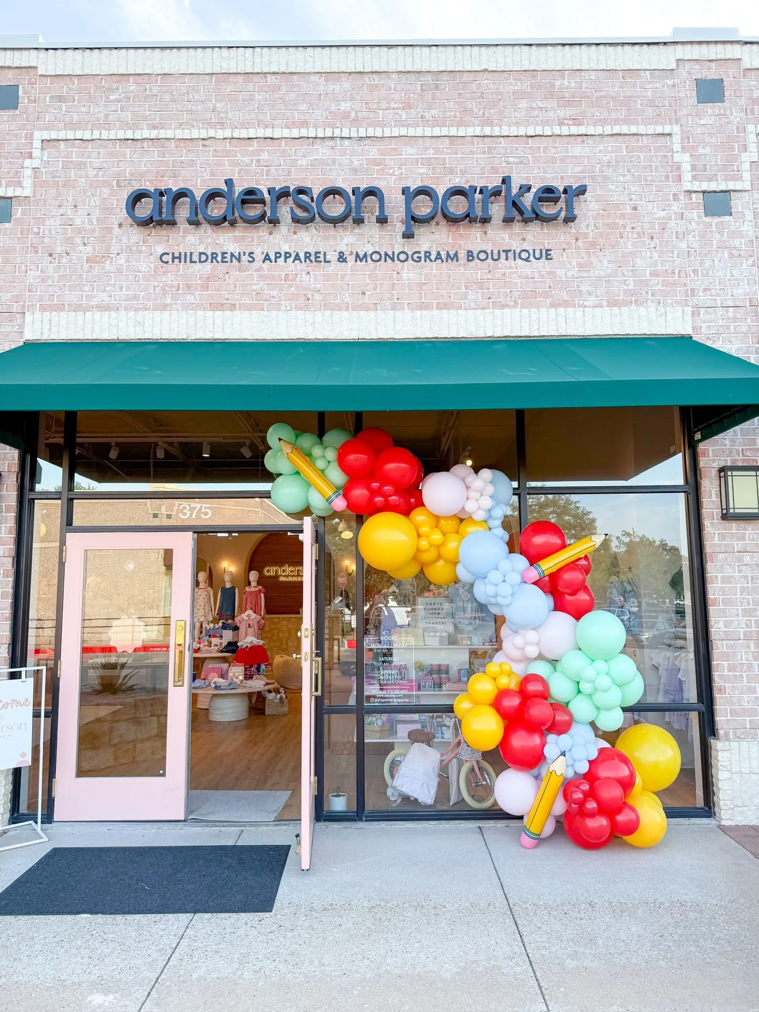 Rainbow balloon garland with pencil balloons on the Anderson Parker children’s boutique storefront