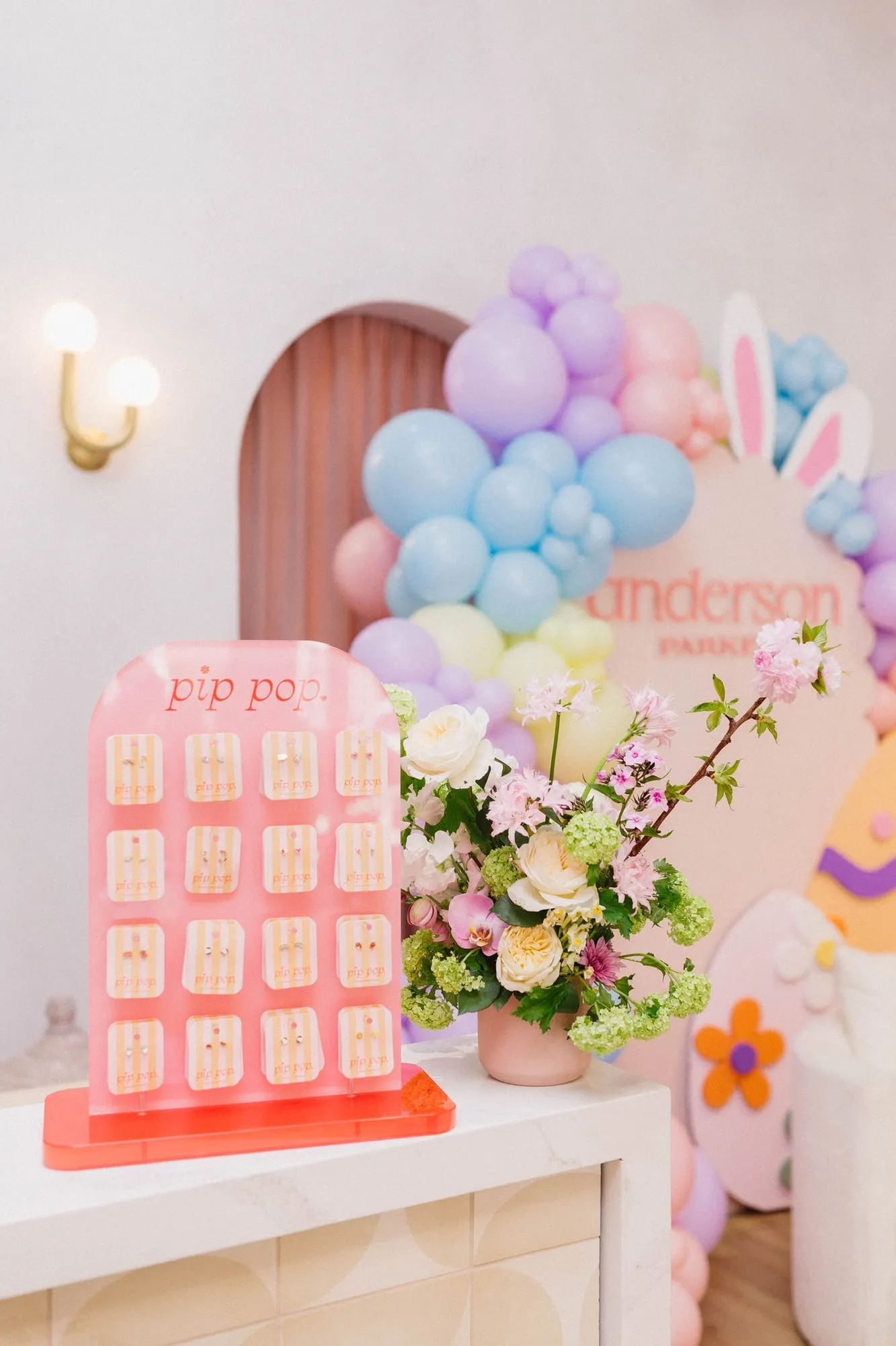 Spring florals and a jewelry display in front of a pastel Easter balloon garland at the Anderson Parker boutique