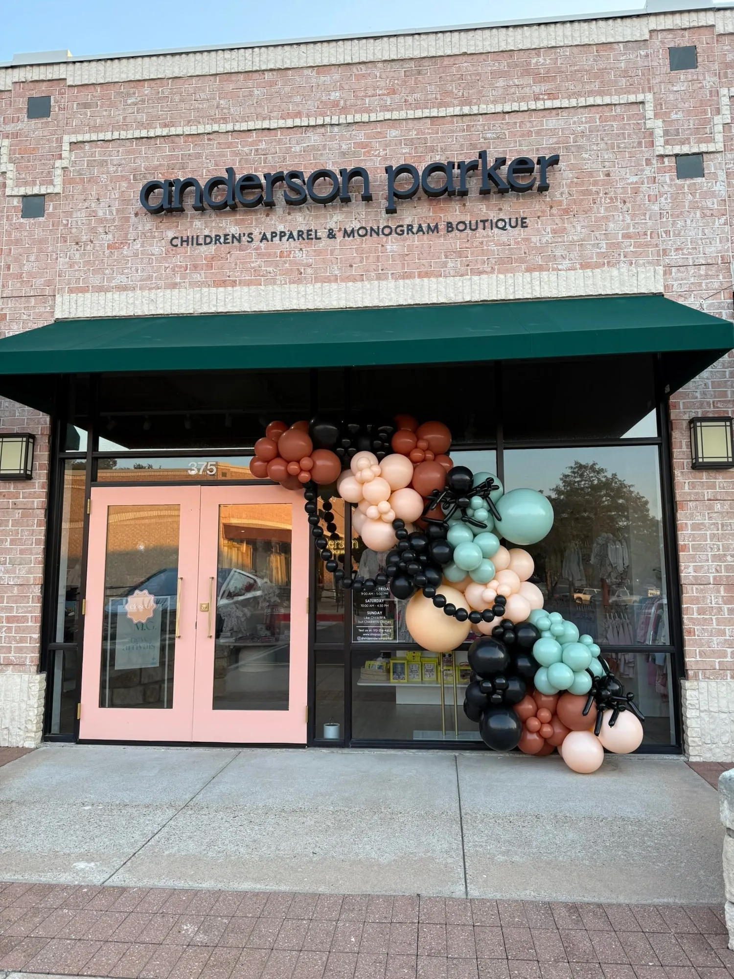 Halloween balloon garland with spider balloons in rust, peach, sage and black on the Anderson Parker boutique storefront