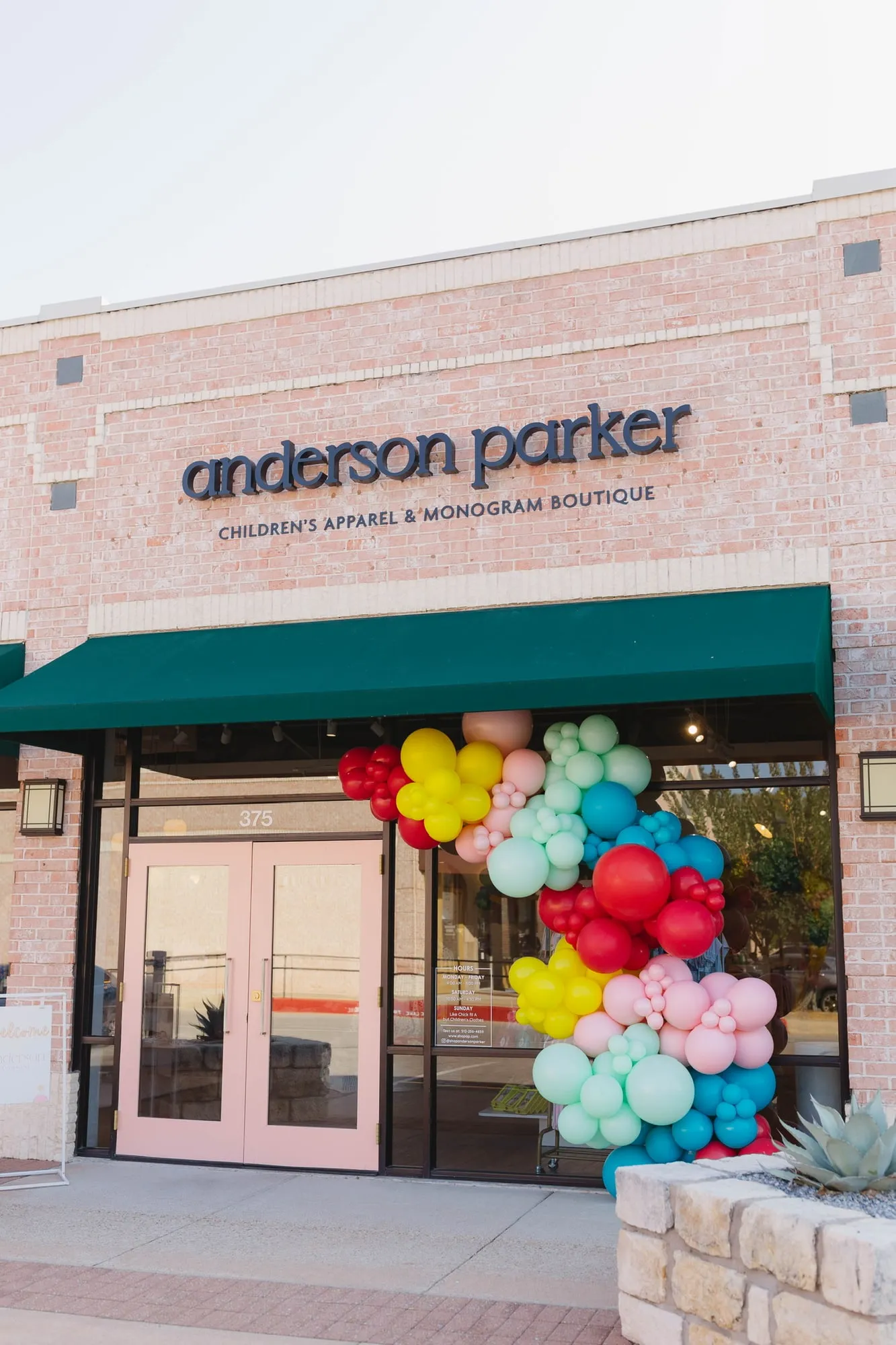 Red, yellow, pink and teal balloon garland on the Anderson Parker children’s boutique storefront