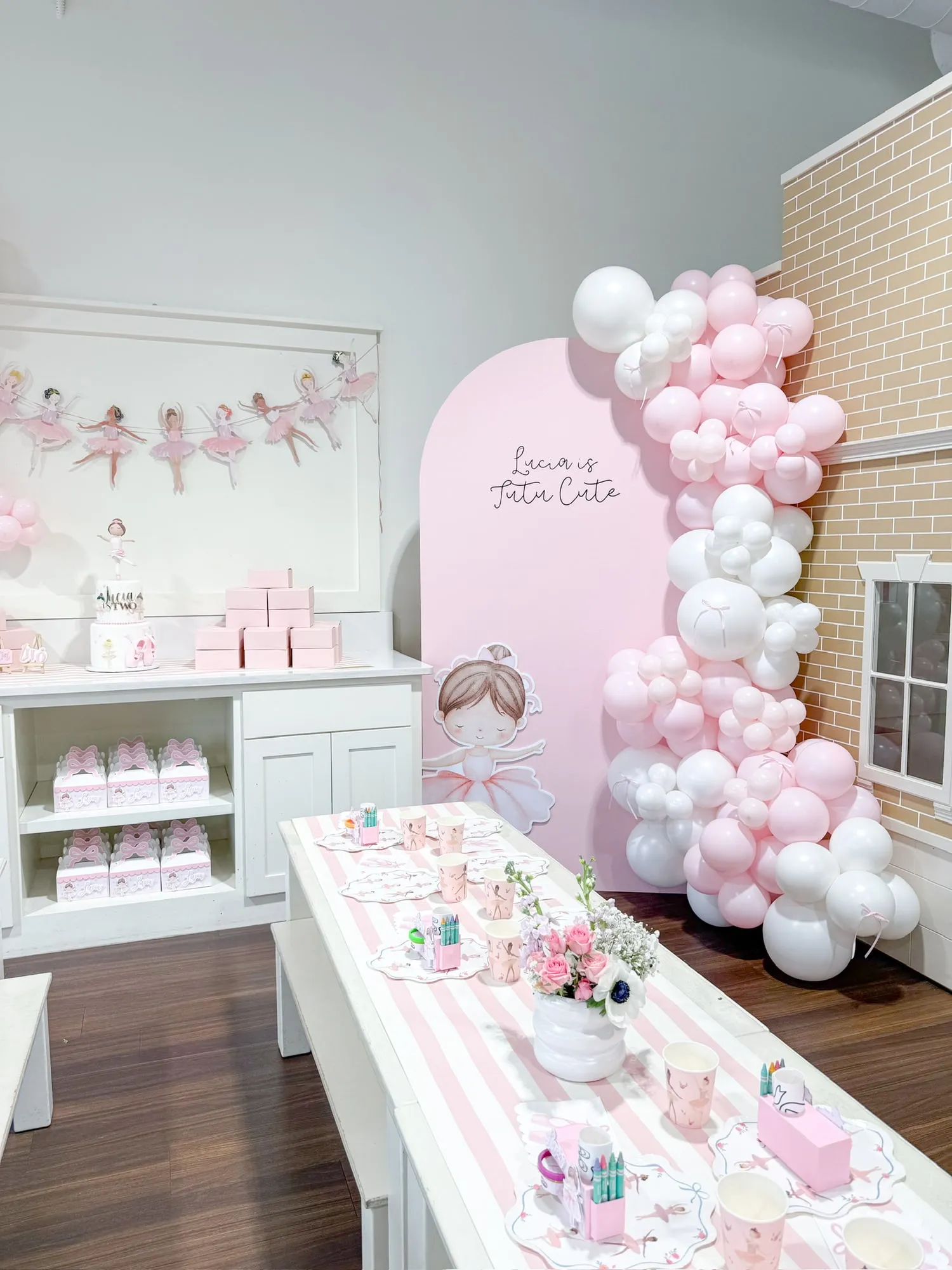 Ballerina themed second birthday with a pink arch backdrop, pink and white balloon garland with bows and a striped kids table
