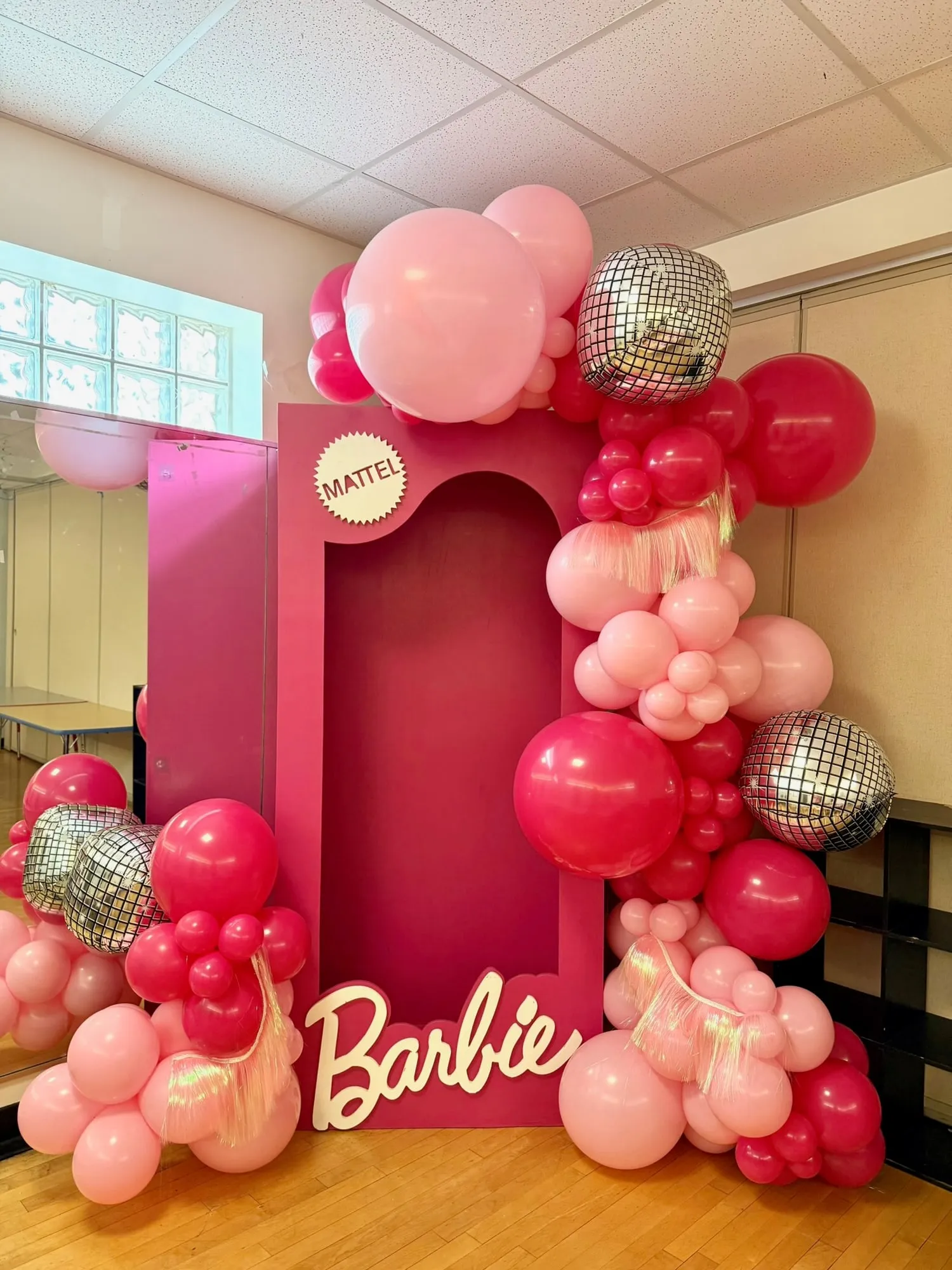 Life size doll box photo booth with pink balloon garland, disco ball balloons and iridescent fringe