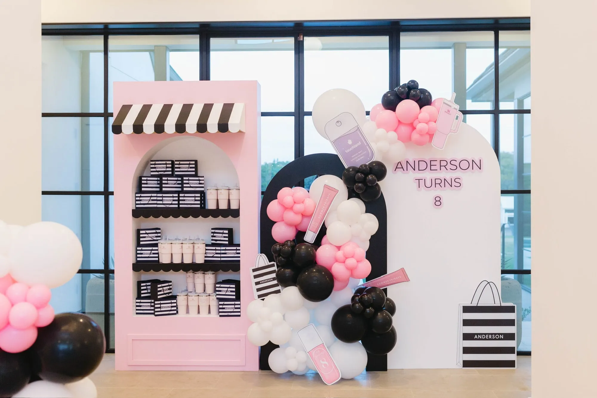 Beauty shop themed eighth birthday with a pink storefront shelf, striped awning and pink, black and white balloon garland