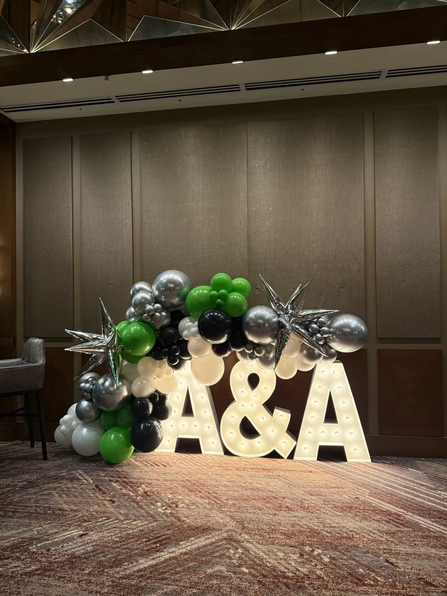 Black, green, white and silver balloon garland with starburst balloons in a hotel ballroom