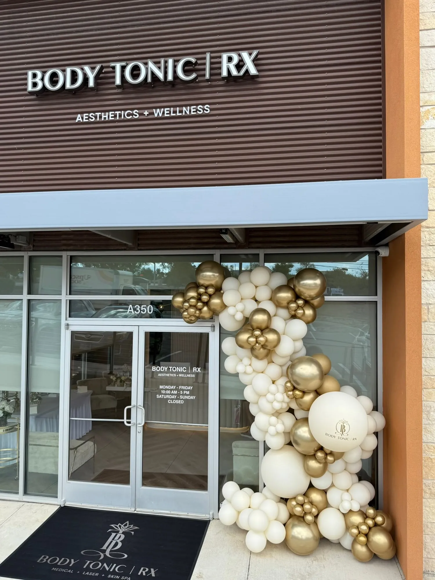 Cream and gold balloon garland with a logo balloon on the Body Tonic RX storefront