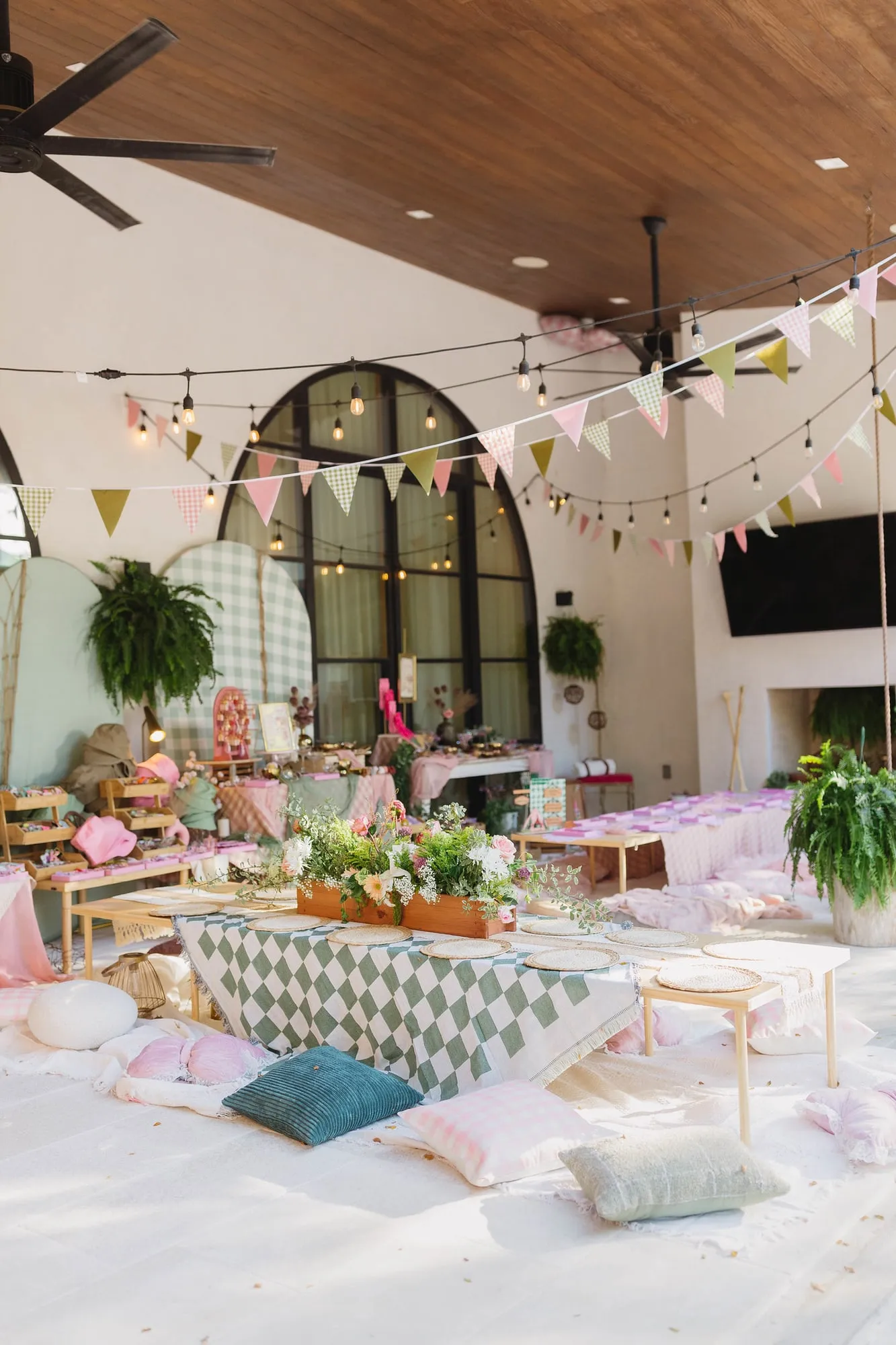 Camp themed birthday with gingham arch backdrops, low picnic tables, floor pillows, florals and pennant bunting
