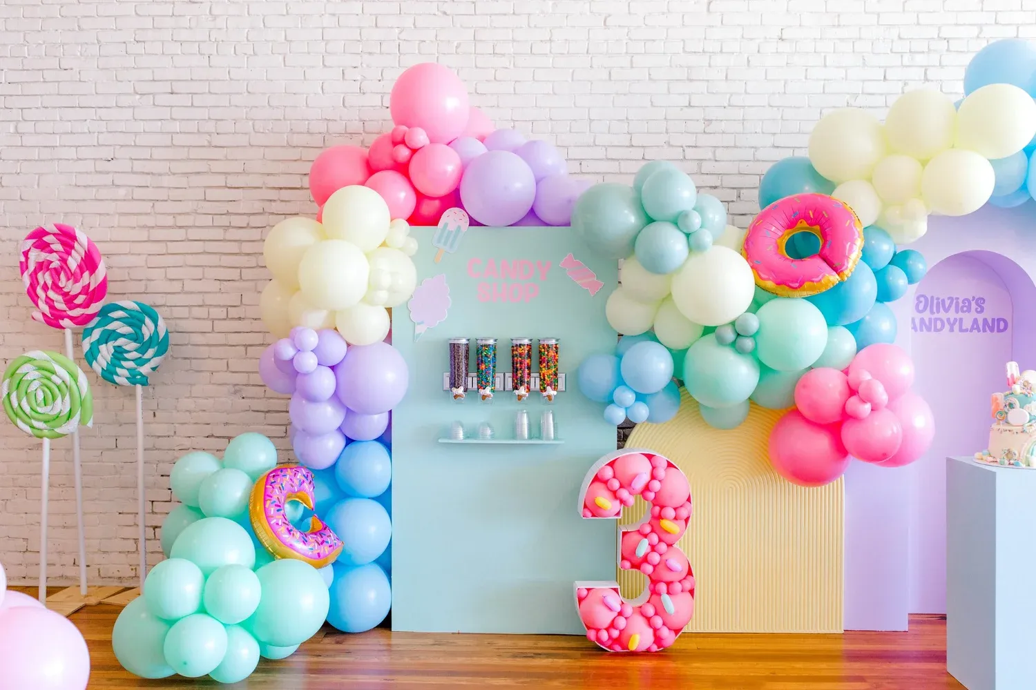 Candy land third birthday with pastel balloon garland, candy shop backdrop, donut balloons and giant number 3