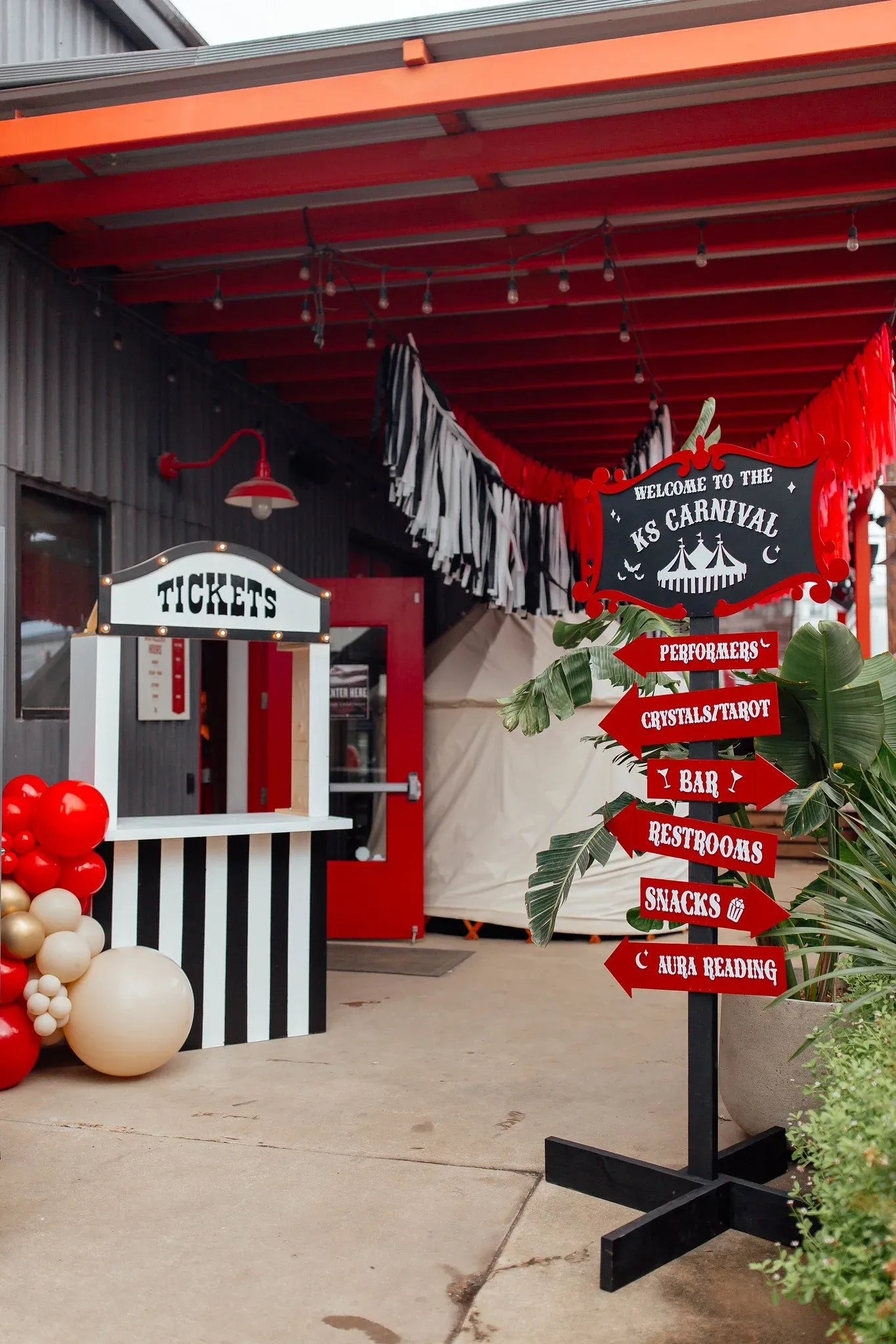 Striped carnival ticket booth and custom directional sign at a corporate event in Austin