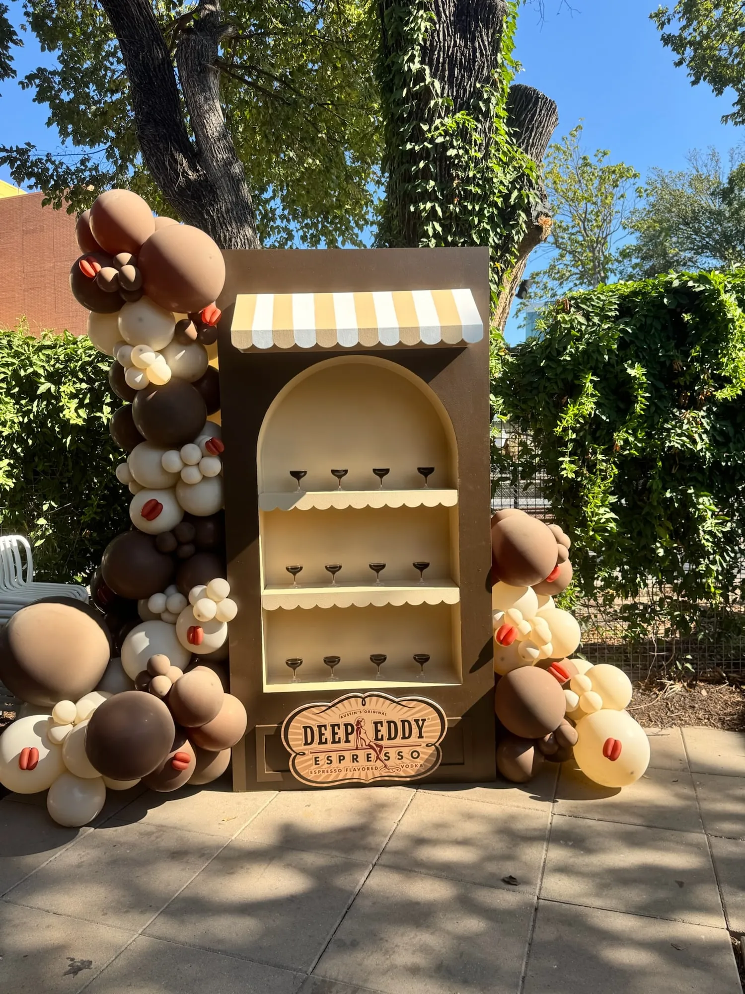 Deep Eddy Espresso vodka activation with a striped awning shelf of espresso martinis and a brown, mocha and cream balloon garland with coffee bean accents
