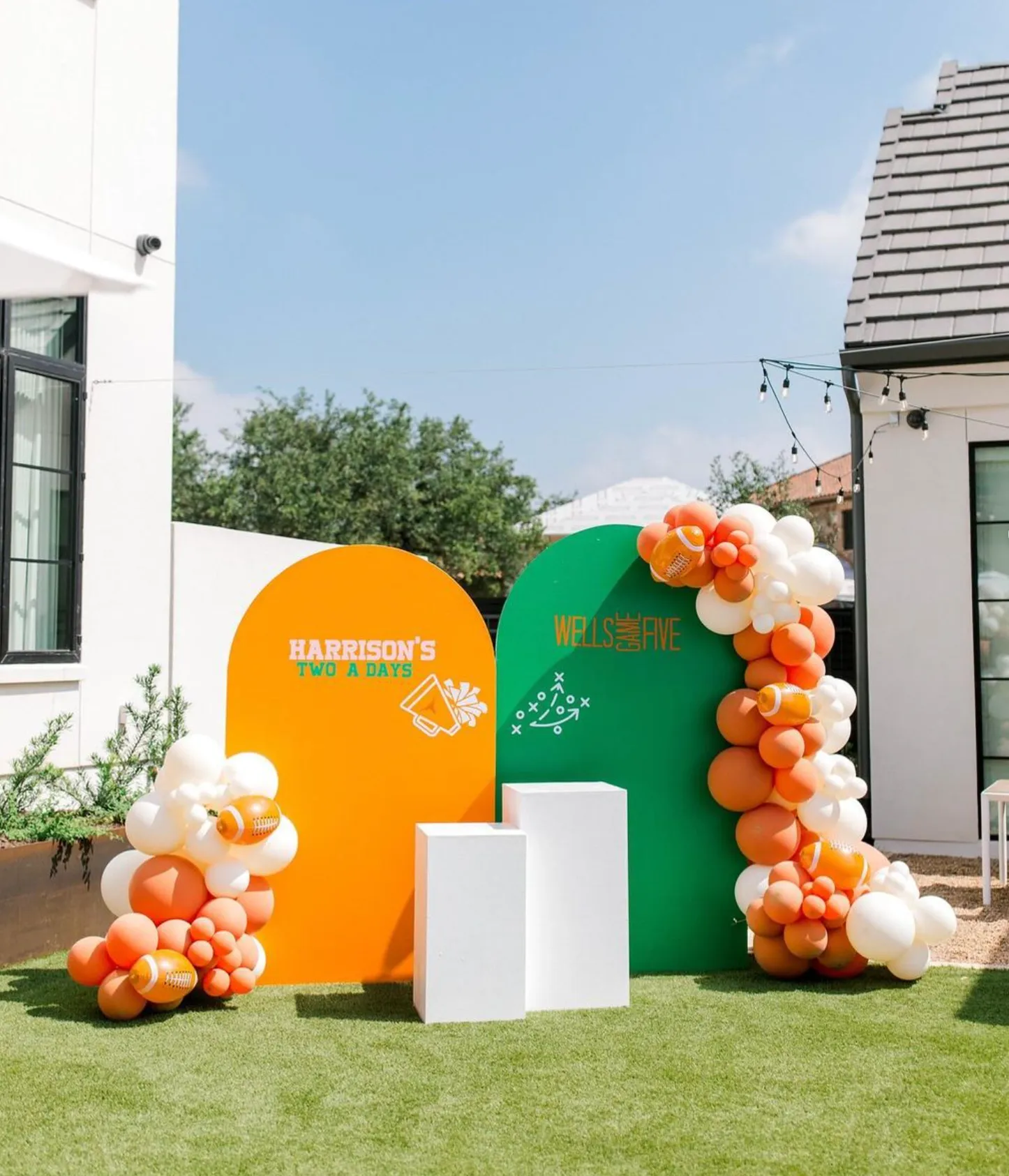 Orange and green arch backdrops with football balloons and white pedestals for a sports birthday