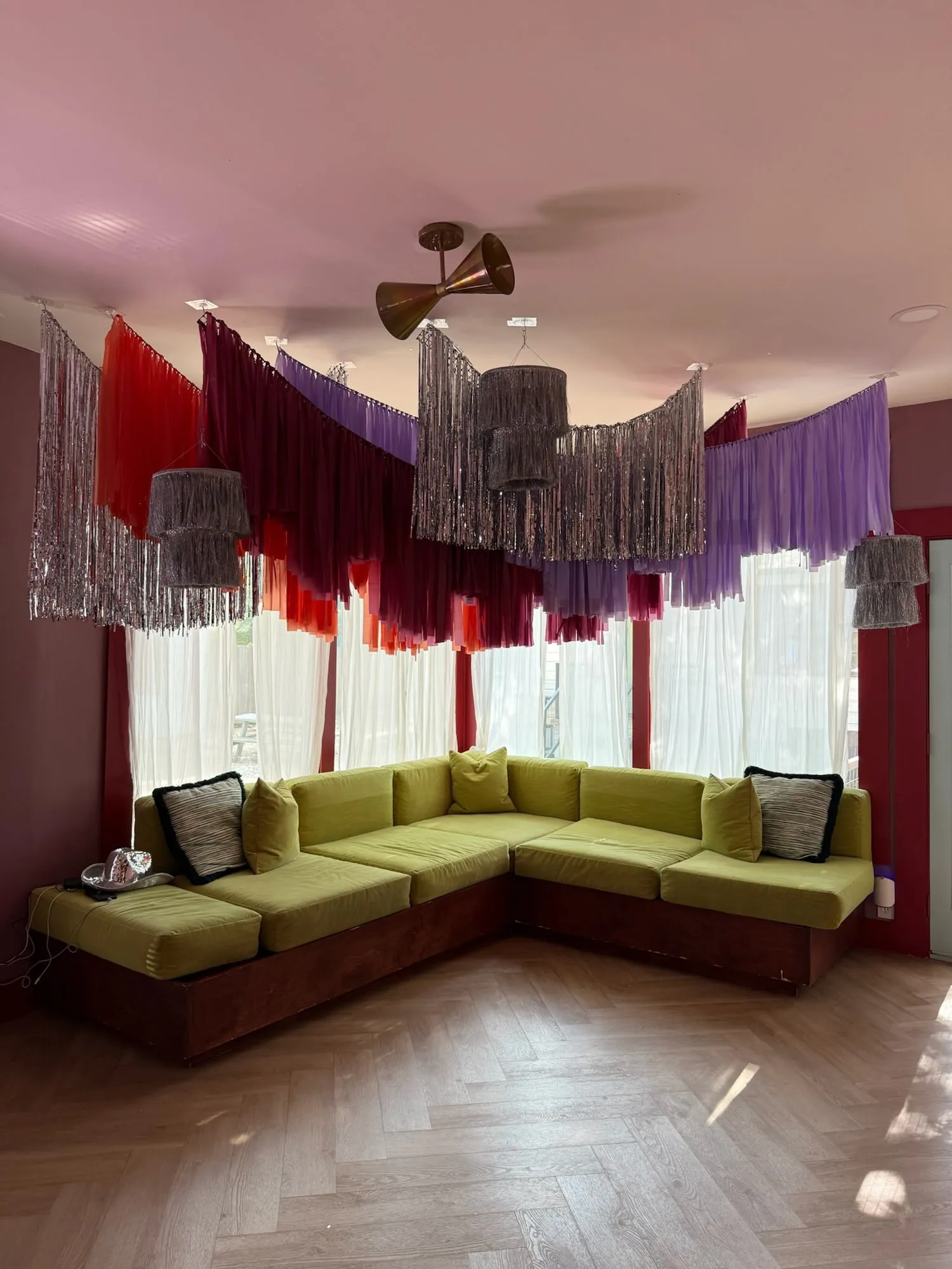 Silver, red, burgundy and lavender fringe streamer ceiling installation with tiered fringe chandeliers over a lounge