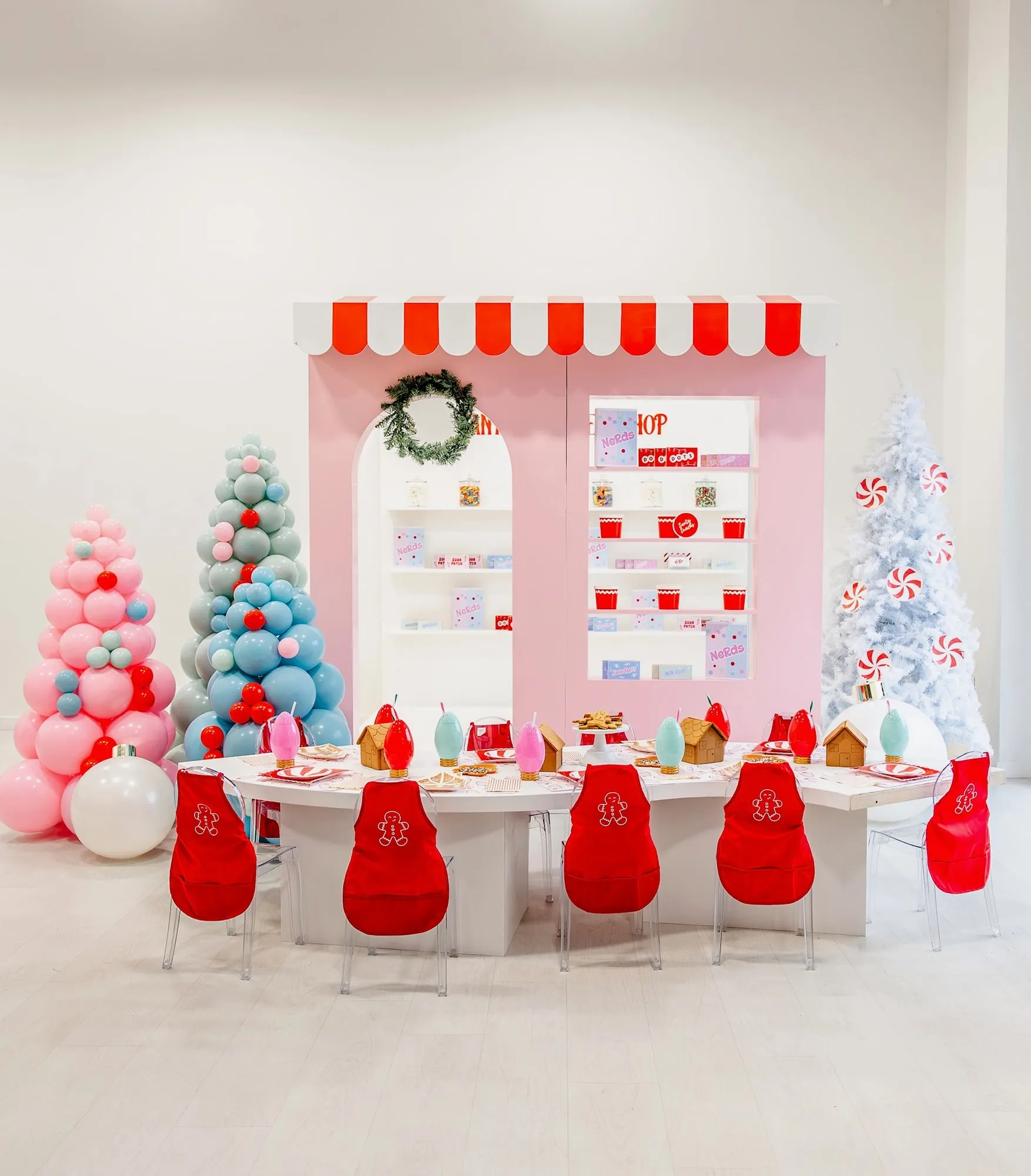 Holiday candy shop backdrop with balloon Christmas trees, a peppermint tree and a gingerbread decorating kids table
