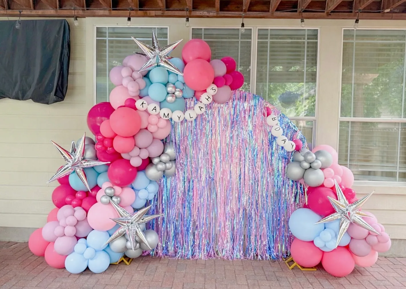 Iridescent fringe arch with pink, lilac and blue balloon garland, silver star balloons and letter balloons