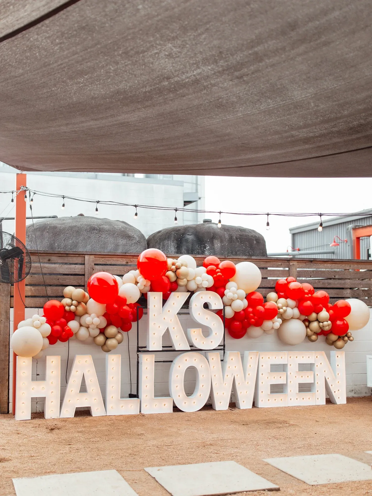 Lighted marquee letters with red, cream and gold balloon garland at a corporate Halloween event