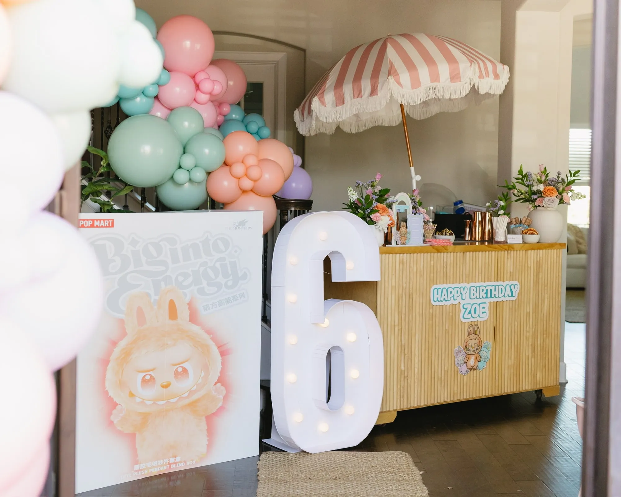 Bamboo bar cart with a striped fringe umbrella, florals and a pastel balloon garland
