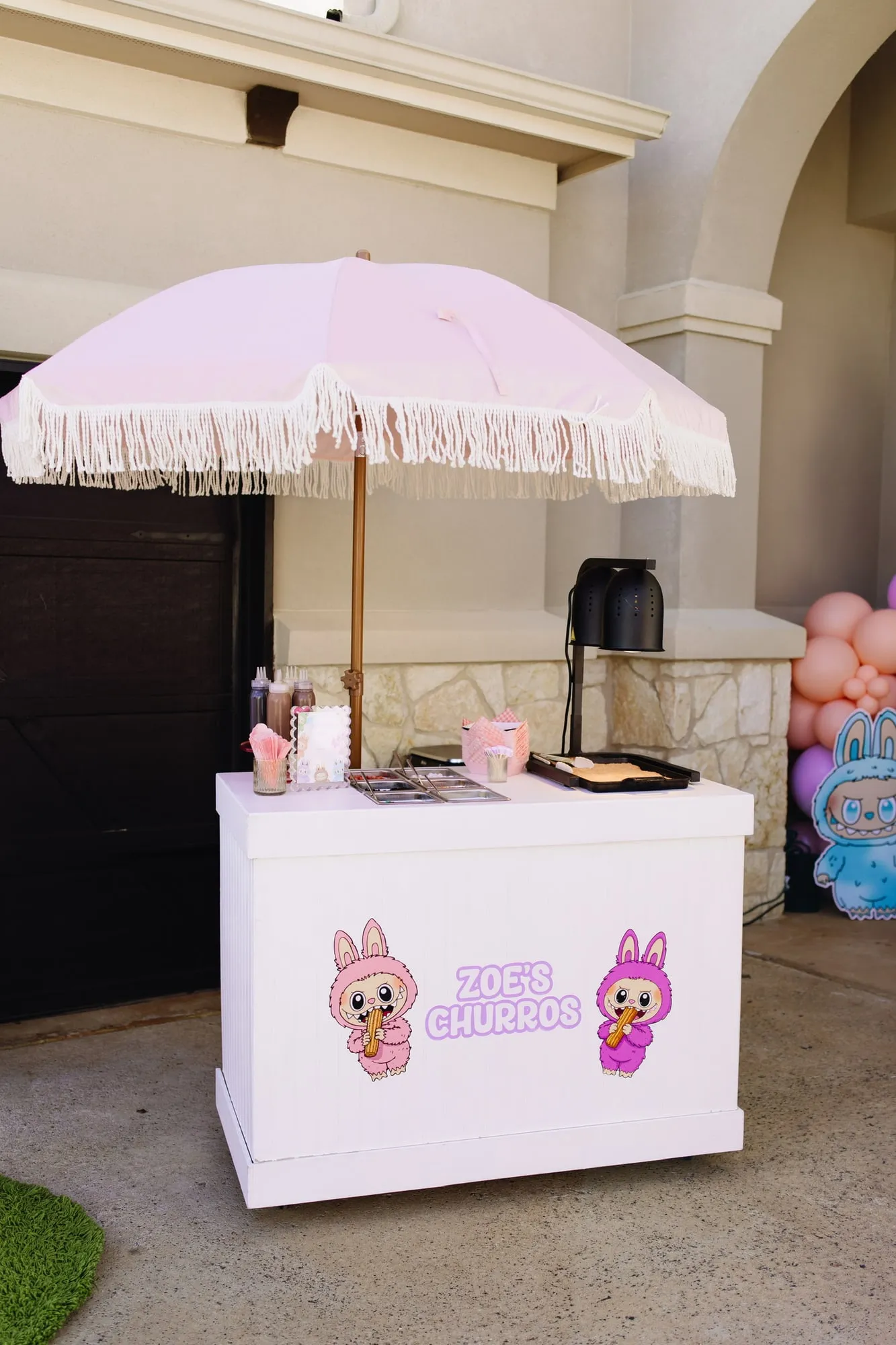 Custom churro cart with a pink fringe umbrella and themed signage