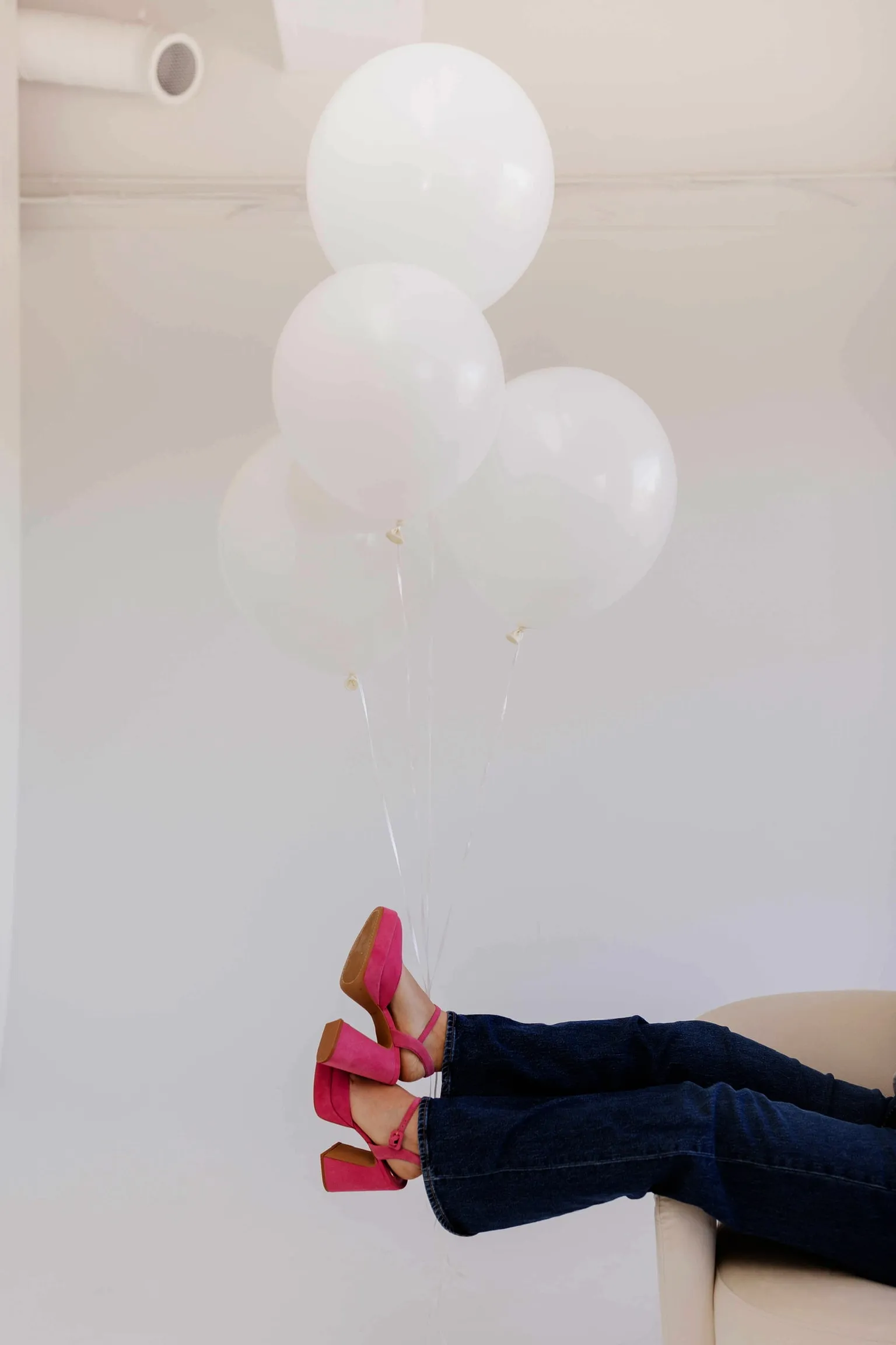 Pink platform heels propped up beside a bunch of white balloons