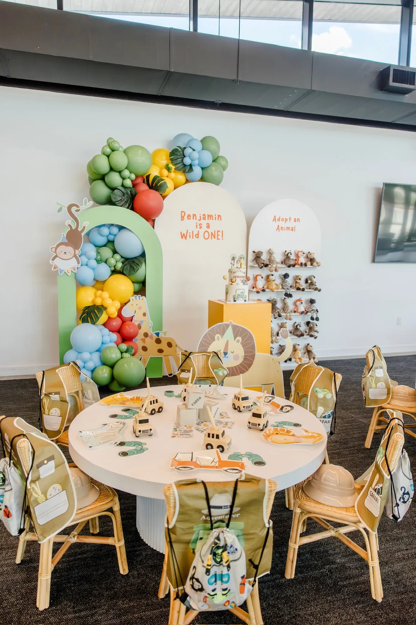 Safari Wild One first birthday with green arch backdrops, jungle balloon garland, adopt an animal wall and a styled kids table