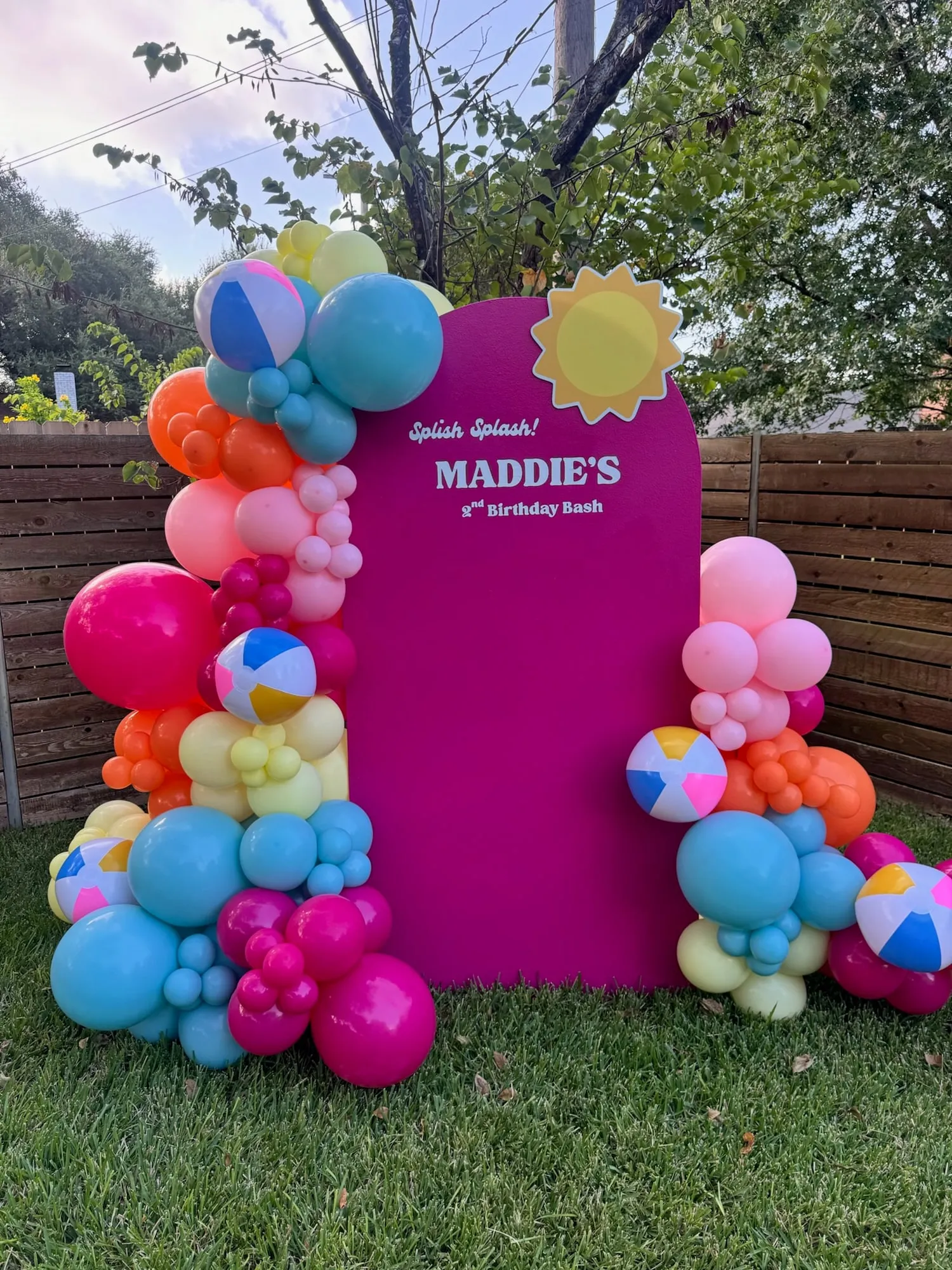 Splish splash second birthday with a magenta arch, sun cutout and bright balloon garland with beach balls