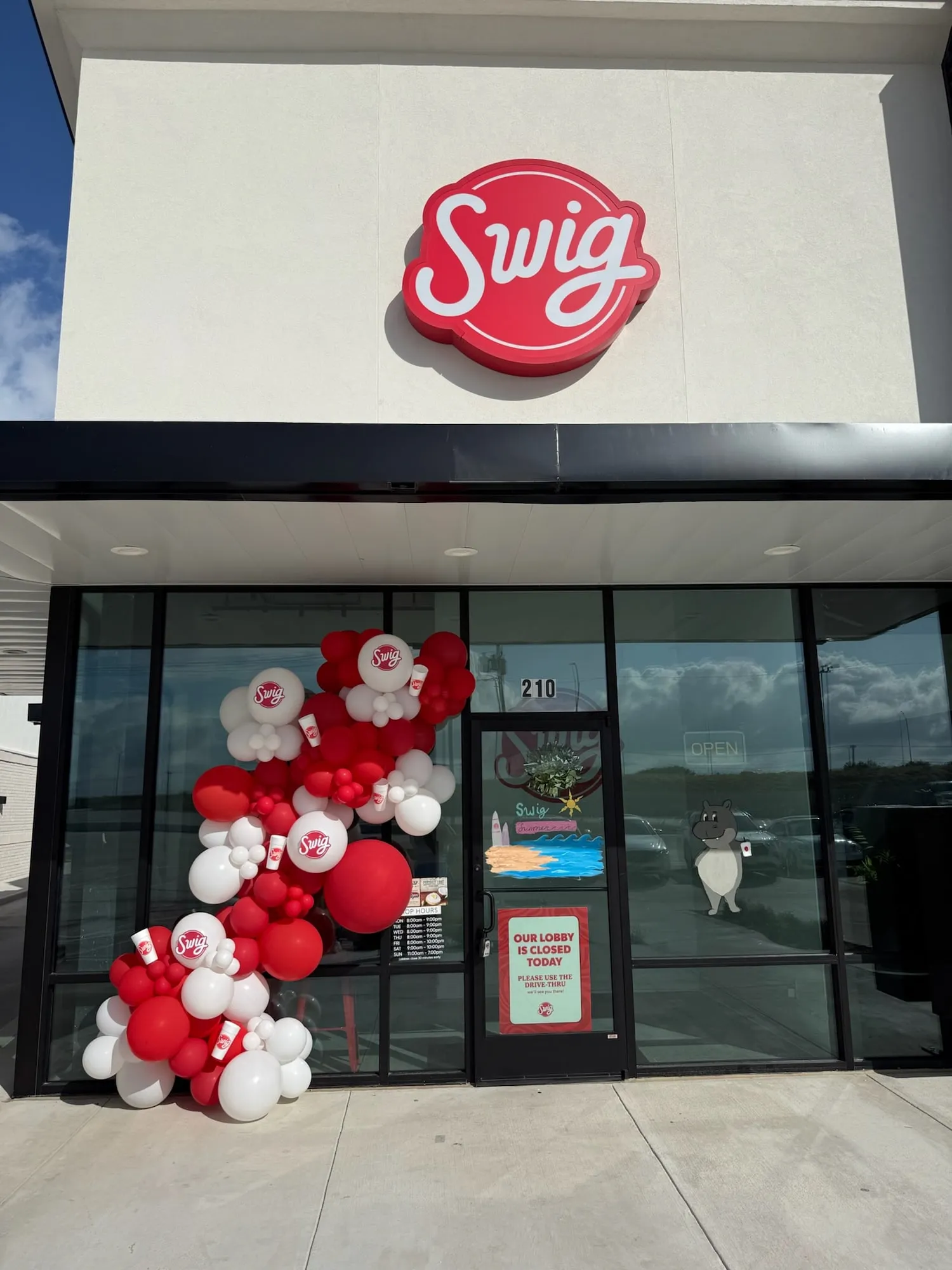 Red and white balloon garland with branded balloons and cups on the Swig dirty soda storefront