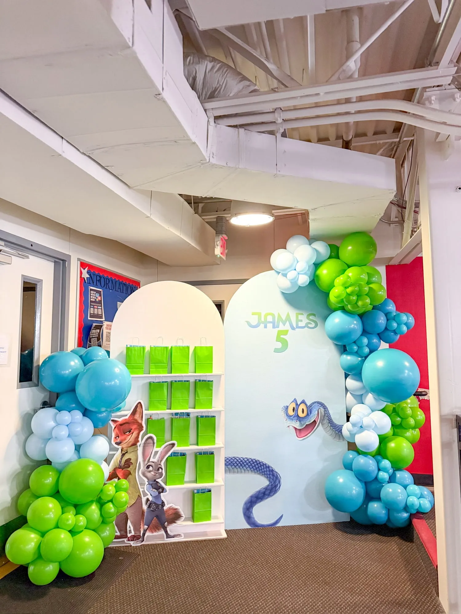 Animal city themed fifth birthday with arch backdrops, a favor bag shelf and blue, white and lime balloon garland